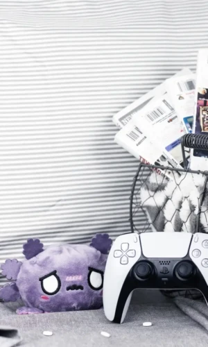 Three Cozy Games to Play When You're Sick cozy games in a basket with a controller and a plushie to play when you're sick
