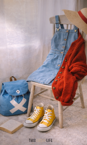 Closet Cosplay: Subtle Everyday Fashion Inspired by the Characters You Love Luffy Inspired Closet Cosplay - blue denim dress, red cardigan, yellow sneakers, blue Chopper backpack, and a straw beach hat on a chair - from This Geek Life Blog